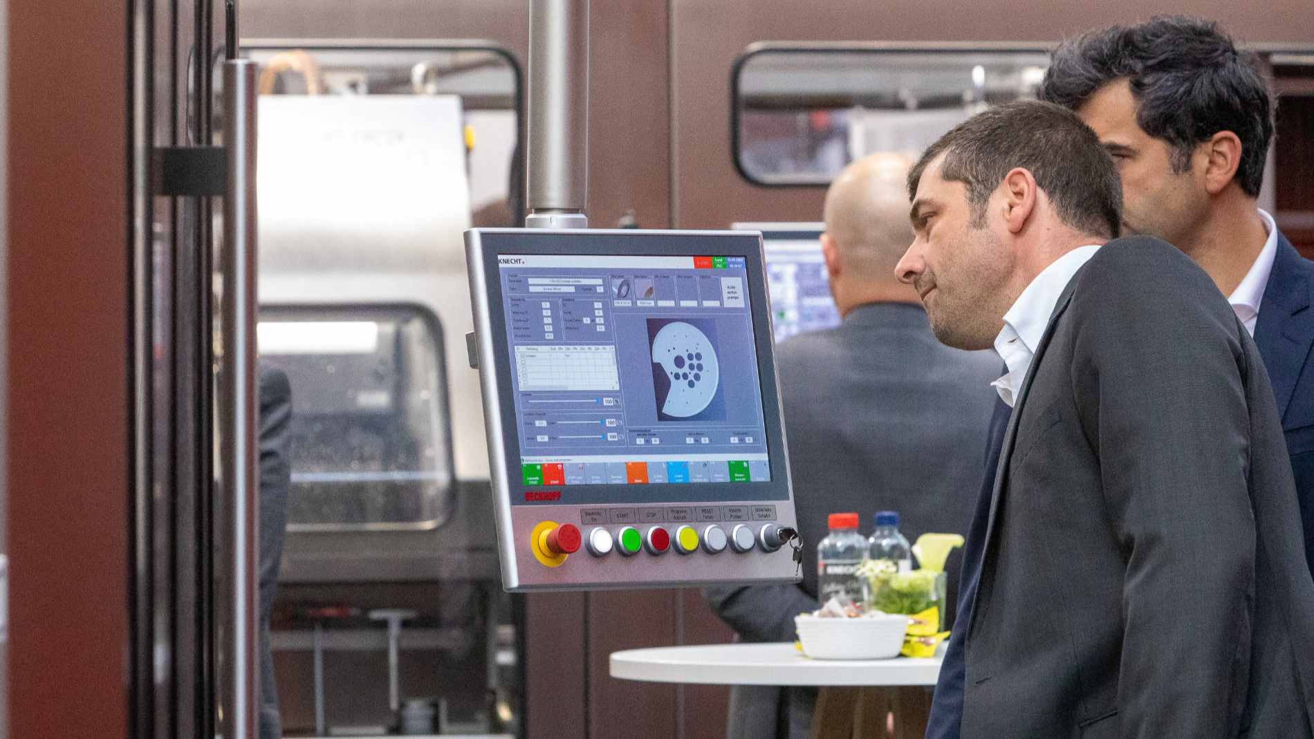 Trade fair visitors stand in front of a monitor